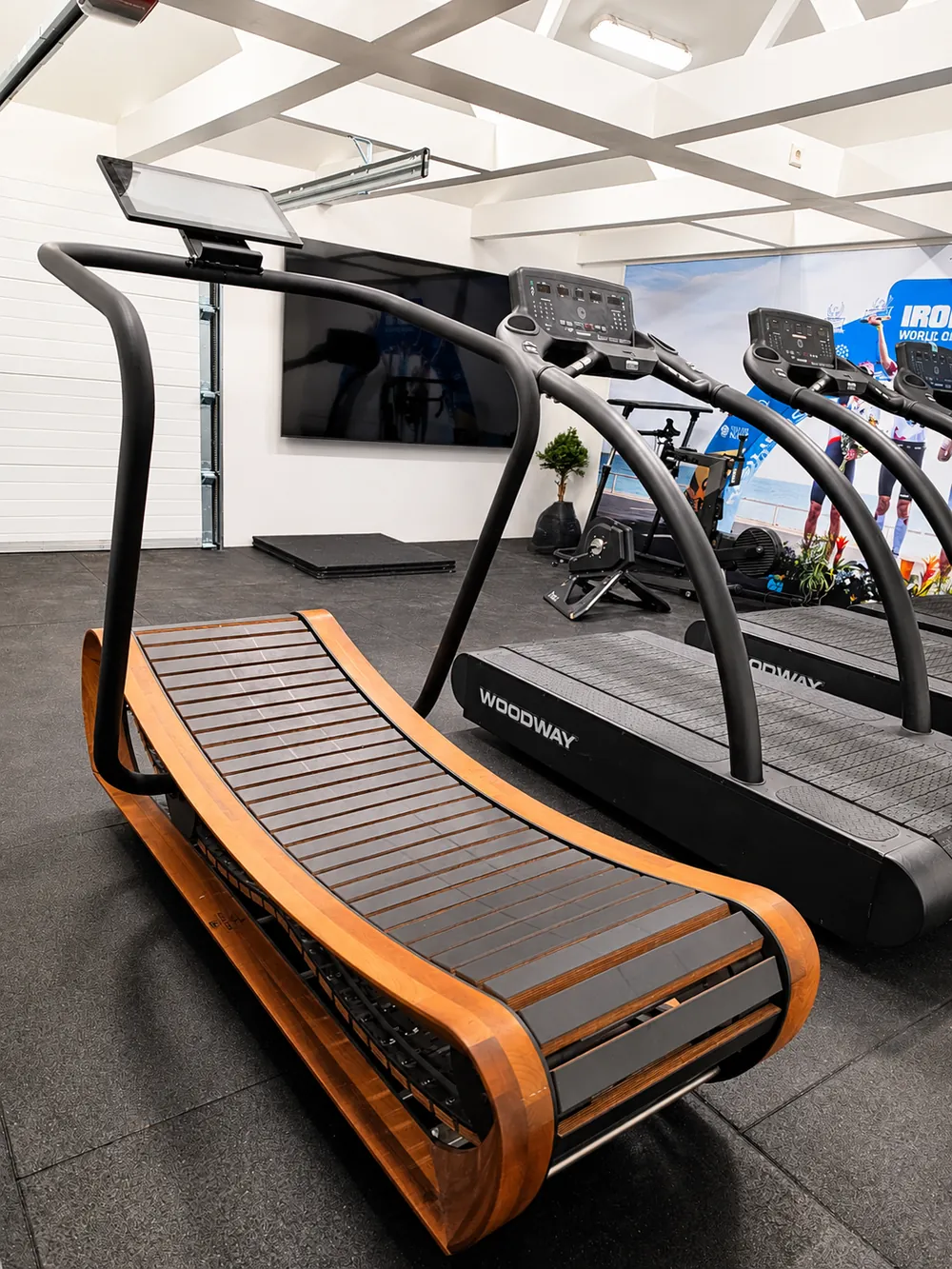 Private garage gym with three Woodway treadmills, a wooden NOHrD treadmill and smart bikes